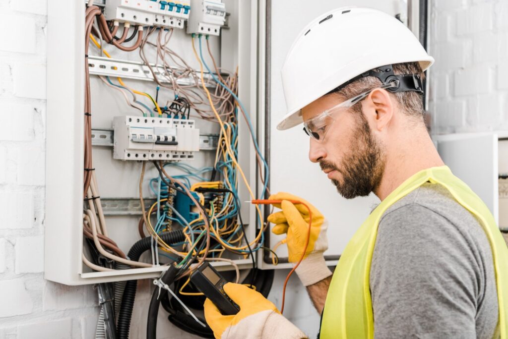 Handsome-Electrician-Checking-Electrical-Box-With-Multimetr-In-Corridor-E
